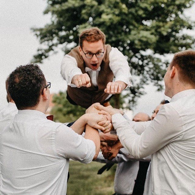 Freunde werfen den Bräutigam bei der Hochzeit in die Luft