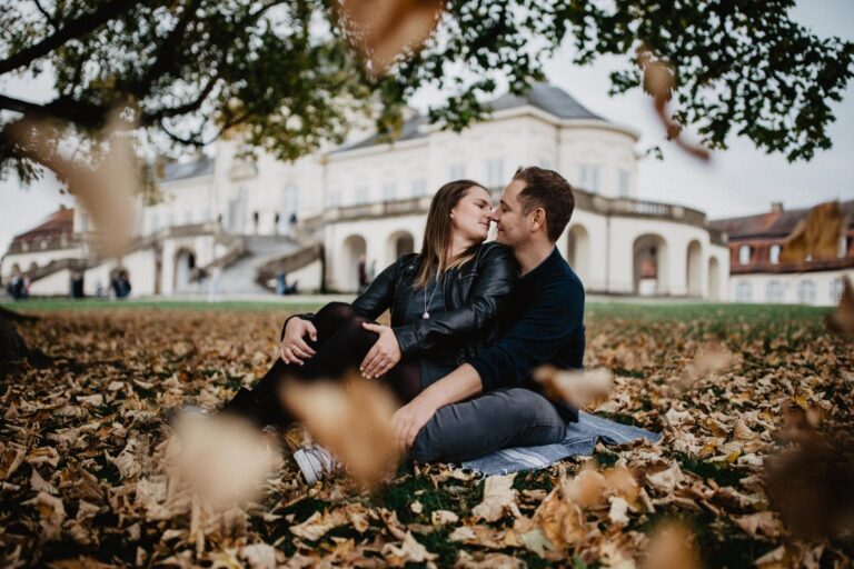 Paar sitzt im Herbstlaub vor Schloss Solitude in Stuttgart