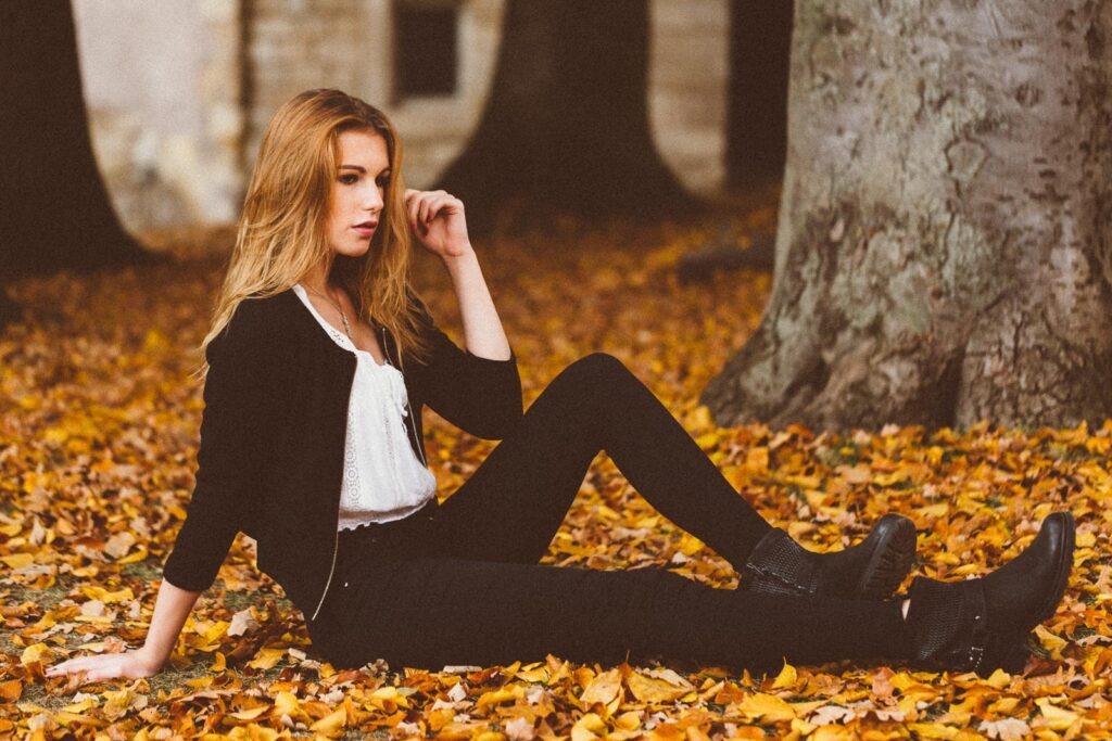 Frau sitzt im Herbstlaub